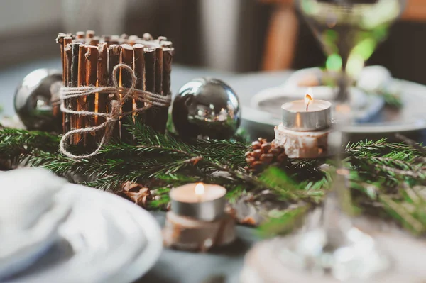 Tovaglia natalizia e Capodanno in stile scandinavo con dettagli rustici fatti a mano in toni naturali e bianchi. Sala da pranzo decorata con pigne, rami e candele — Foto Stock