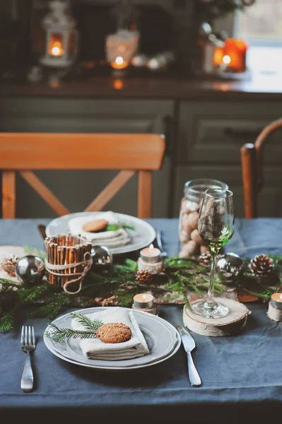 Cenário festivo de mesa de Natal e Ano Novo em estilo escandinavo com detalhes artesanais rústicos em tons naturais e brancos. Lugar de jantar decorado com cones de pinho, ramos e velas — Fotografia de Stock