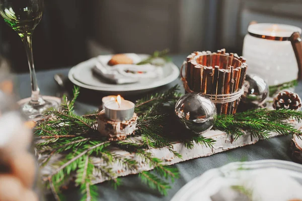 Festive Christmas and New Year table setting in scandinavian style with rustic handmade details in natural and white tones. Dining place decorated with pine cones, branches and candles — Stock Photo, Image