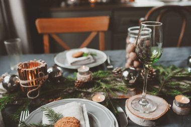 Şenlikli Noel ve Yeni Yıl sofrası İskandinav tarzında hazırlandı. Kırsal ve beyaz tonlarda el yapımı detaylarla. Çam kozalakları, dallar ve mumlarla süslenmiş yemek salonu.