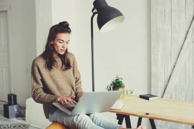 genç güzel kadın evde laptop ve kahve ile sabah alışveriş online. Modern İskandinav iç ev ofis