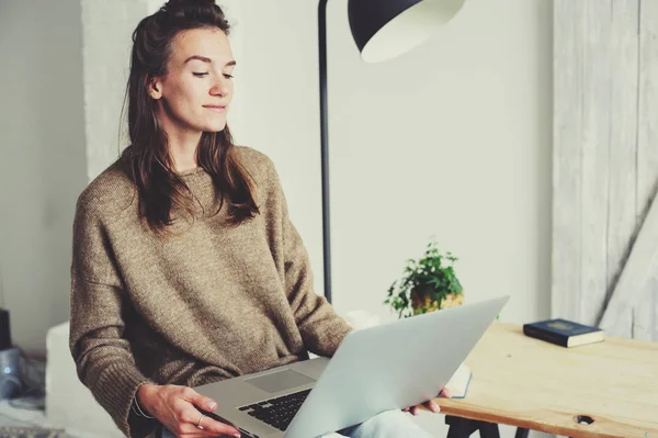 Young beautiful woman shopping at home online with laptop and cup of coffee in the morning. Home office in modern scandinavian interior — Stock Photo, Image