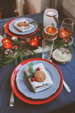 Neşeli Noel ve yeni yıl ayar kırmızı ve gri tonlarda masa. El yapımı rustik ayrıntıları ve mumlar ile kutlama için yemek yer 
