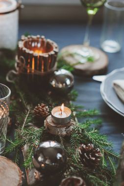 Şenlikli Noel ve Yeni Yıl sofrası İskandinav tarzında hazırlandı. Kırsal ve beyaz tonlarda el yapımı detaylarla. Çam kozalakları, dallar ve mumlarla süslenmiş yemek salonu.