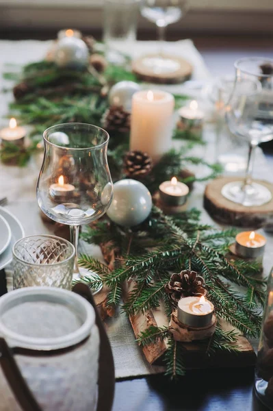 Cenário festivo de mesa de Natal e Ano Novo em estilo escandinavo com detalhes artesanais rústicos em tons naturais e brancos. Lugar de jantar decorado com cones de pinho, ramos e velas — Fotografia de Stock