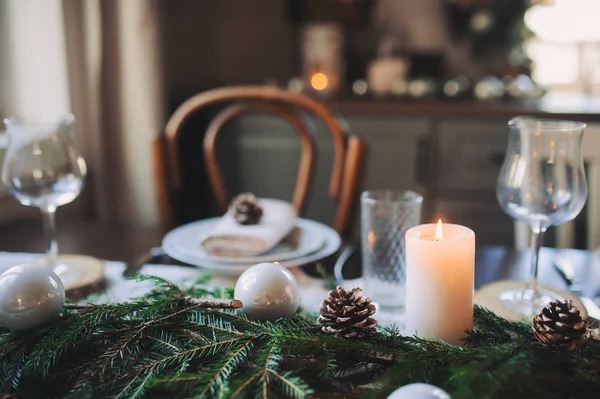 Tovaglia natalizia e Capodanno in stile scandinavo con dettagli rustici fatti a mano in toni naturali e bianchi. Sala da pranzo decorata con pigne, rami e candele — Foto Stock