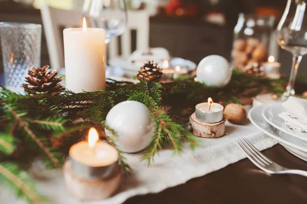 Tovaglia natalizia e Capodanno in stile scandinavo con dettagli rustici fatti a mano in toni naturali e bianchi. Sala da pranzo decorata con pigne, rami e candele — Foto Stock