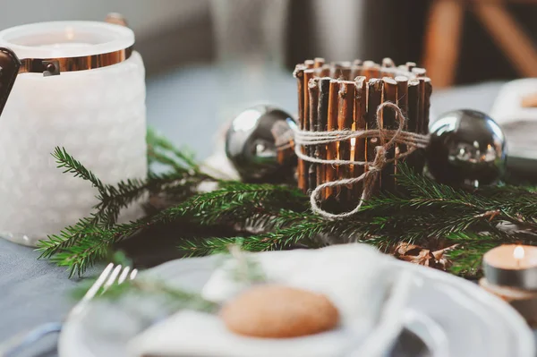 Festive Christmas and New Year table setting in scandinavian style with rustic handmade details in natural and white tones. Dining place decorated with pine cones, branches and candles — Stock Photo, Image