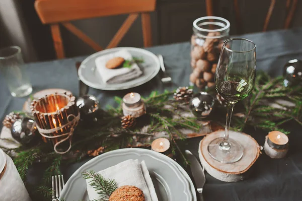 Jule- og nyttårsbordsetting i skandinavisk stil med rustikke håndlagde detaljer i naturlige og hvite toner. Restaurant dekorert med kongler, grener og stearinlys – stockfoto