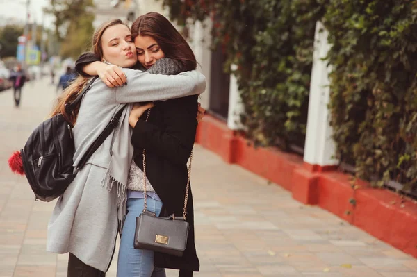 Twee jonge gelukkig vriendinnen wandelen op de straten van de stad in casual mode outfits, het dragen van warme jassen en plezier — Stockfoto