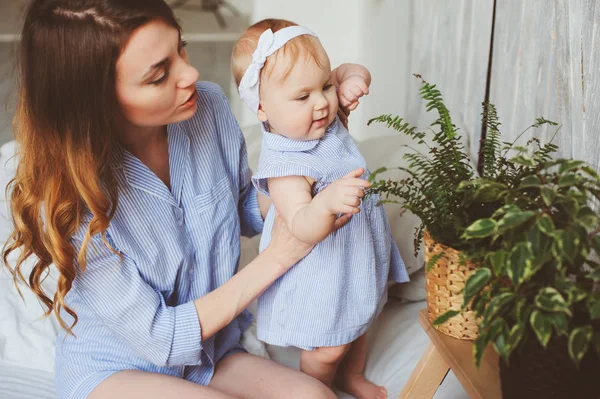 Mère heureuse et bébé de 9 mois en pyjama assorti jouant dans la chambre le matin. Week-end familial confortable . — Photo