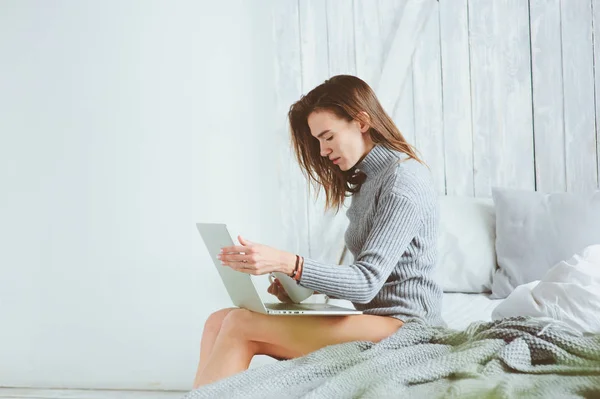 年轻的博客写手或商业女性在家里和社交媒体一起工作, 清晨在床上喝咖啡。现代生活在斯堪的纳维亚内部, 休闲生活方式 — 图库照片