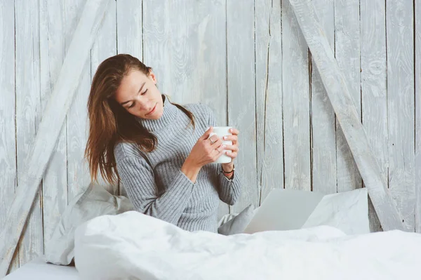Young blogger or business woman working at home with social media, drinking coffee in early morning in bed. Modern living in scandinavian interior, casual lifestyle — Stock Photo, Image