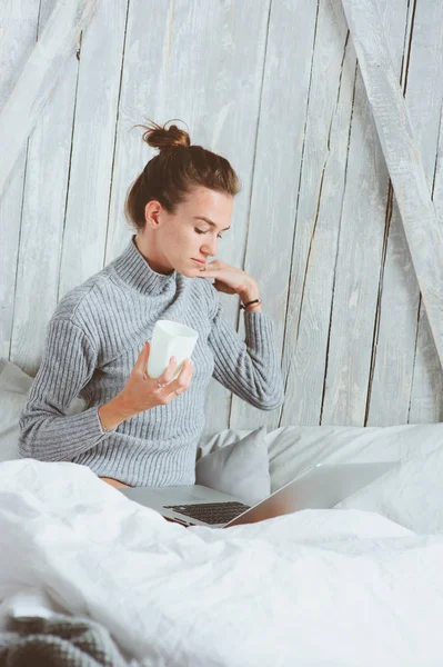 Joven blogger o mujer de negocios que trabaja en casa con las redes sociales, bebiendo café por la mañana temprano en la cama. La vida moderna en el interior escandinavo, estilo de vida casual — Foto de Stock