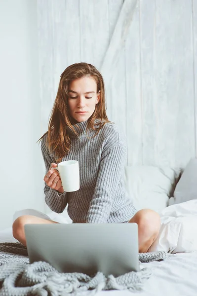 年轻的博客写手或商业女性在家里和社交媒体一起工作, 清晨在床上喝咖啡。现代生活在斯堪的纳维亚内部, 休闲生活方式 — 图库照片