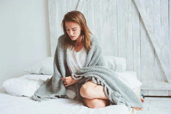 Young sexy woman relaxing at home in bed in cozy winter weekend morning, wrapped in warm knitted blanket — Stock Photo, Image