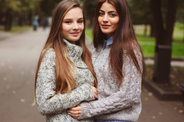 iki genç mutlu kız rahat moda kıyafetler içinde şehrin sokaklarında yürürken, sıcak kazak giyen ve having fun