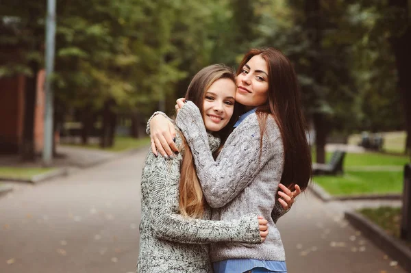 Twee jonge gelukkig vriendinnen wandelen op de straten van de stad in casual mode outfits, warme truien dragen en plezier — Stockfoto