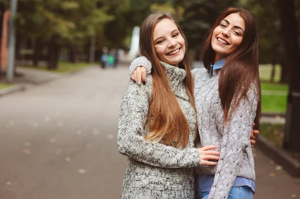 Due giovani amiche felici che passeggiano per le strade della città in abiti casual, indossando maglioni caldi e divertendosi — Foto Stock