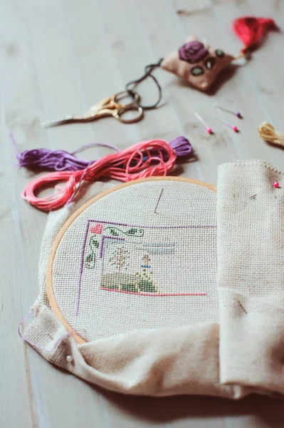 Cross stitch set in process. hoop with embroidered pattern, scissors, canvas and colorful yarn. Selective focus. Handmade and hobby concept. — Stock Photo, Image