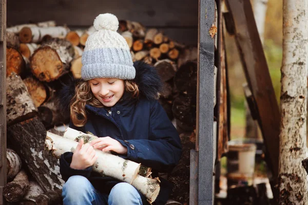 Bambino felice ragazza raccogliere legna da ardere da capannone in inverno o in autunno — Foto Stock