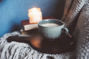 Evde rahat kış hafta sonu. Sabah kahve veya kakao, kitaplar, sıcak battaniye ve İskandinav tarzı sandalye ördü. Hygge kavramı.