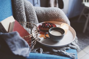 Evde rahat kış hafta sonu. Sabah kahve veya kakao, kitaplar, sıcak battaniye ve İskandinav tarzı sandalye ördü. Hygge kavramı.
