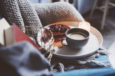 Evde rahat kış hafta sonu. Sabah kahve veya kakao, kitaplar, sıcak battaniye ve İskandinav tarzı sandalye ördü. Hygge kavramı.