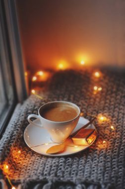 Kış veya sonbahar sabahı evde rahat. Sıcak kahve altın metal kaşık, sıcak battaniye, garland ve mum ışıkları, İsveçli hygge kavramı ile.
