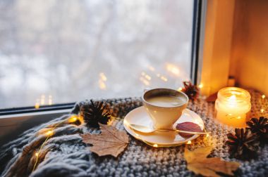 Kış veya sonbahar sabahı evde rahat. Sıcak kahve altın metal kaşık, sıcak battaniye, garland ve mum ışıkları, İsveçli hygge kavramı ile.