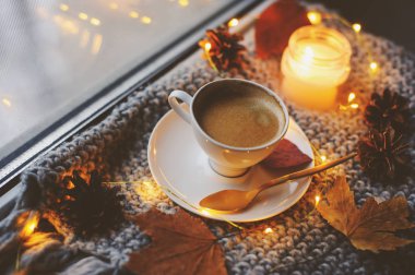 Kış veya sonbahar sabahı evde rahat. Sıcak kahve altın metal kaşık, sıcak battaniye, garland ve mum ışıkları, İsveçli hygge kavramı ile.