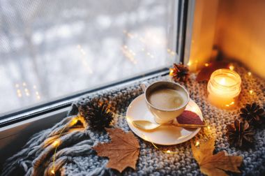 Kış veya sonbahar sabahı evde rahat. Sıcak kahve altın metal kaşık, sıcak battaniye, garland ve mum ışıkları, İsveçli hygge kavramı ile.