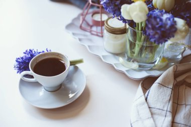 fincan kahve, mumlar ve beyaz masaya çiçek bahar sabah evde. Mevsimlik dekorasyon, rahat yaşam, hygge kavramı
