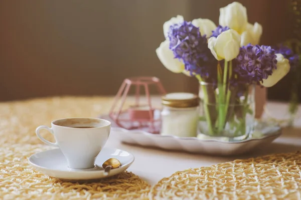 Morning coffee, spring decorations at home on the table in modern scandinavian style with flowers and aromatic candles. Slow living and hygge concept