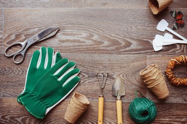 Bahçıvan tablo üstten görünüm araçları, eldiven, turba tencere ve Bahçe etiket üzerinde kahverengi ahşap arka plan bahar. Düz yatıyordu kompozisyon, tohum kesme mevsimlik ürünleri