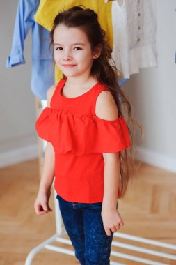 sevimli küçük çocuk kız ona gardırop veya oda uygun mağaza yeni modern giysiler seçmek. Çocuk moda ve giyim depolama kavramı.