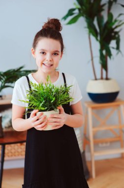 mutlu bir çocukluk kız evde, houseplants dikkat çekici giyinmiş şık siyah-beyaz kıyafeti, tropikal bitkiler üzerinde arka plan ile modern İskandinav iç