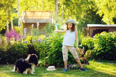 bahçede güneşli yaz günü zevk onun spaniel köpekle oynamayı ve topu, atma mutlu çocuk kız