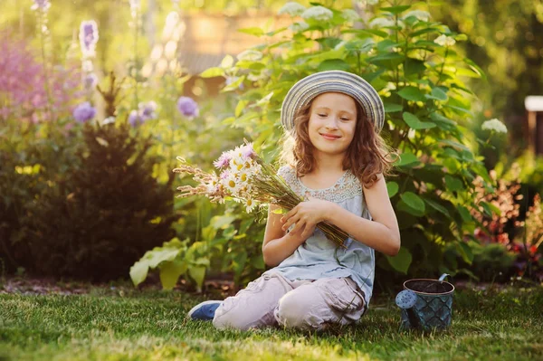 夏に小さい庭師を演奏 面白い帽子をかぶって 花の花束を持って 女の子を幸せな子 屋外の夏季休暇を楽しむ緑の芝生の上に座ってください — ストック写真