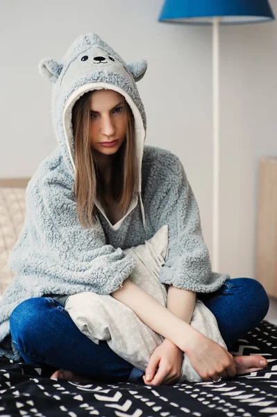 若くてきれいな女性のベッドの家でのんびりおかしい灰色のパーカーを着ています 怠惰な週末の朝に目を覚ます — ストック写真