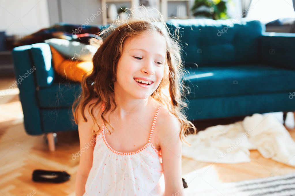 happy child girl playing at home in cozy weekend morning, having fun on couch in modern living room
