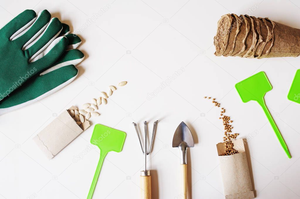 spring garden work flat lay with vegetable seeds in handmade envelopes, labels, peat pots and garden tools on wooden table. Seasonal work and preparations