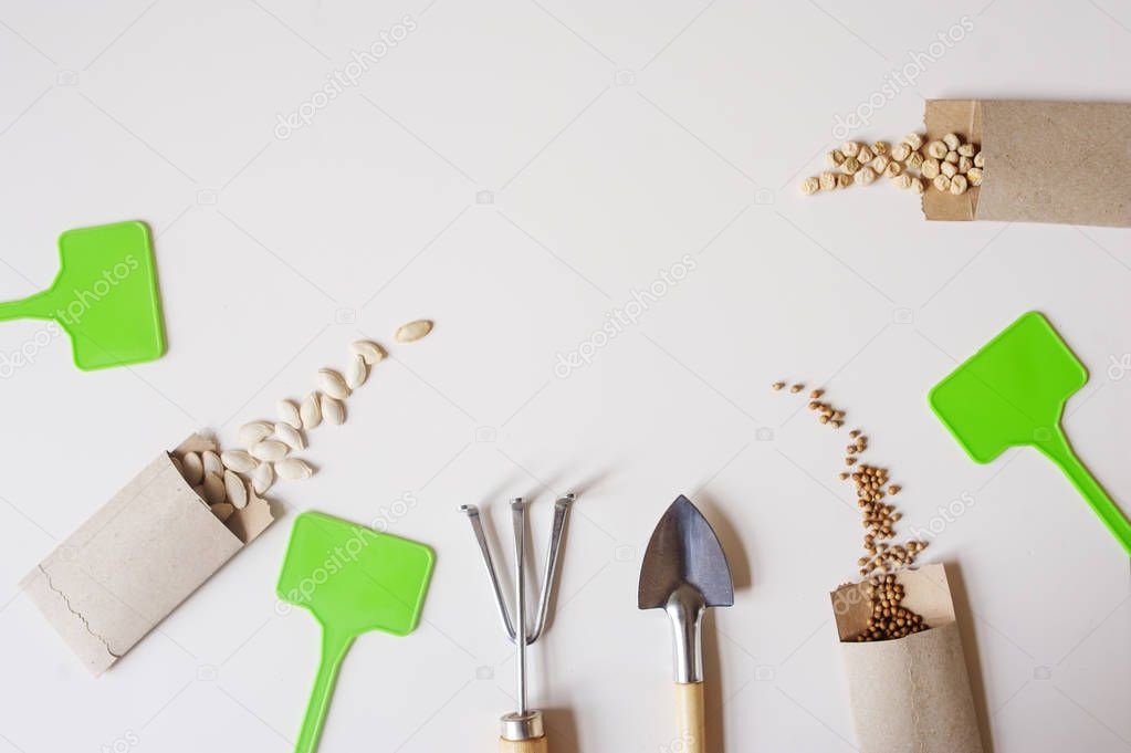 spring garden work flat lay with vegetable seeds in handmade envelopes, labels, peat pots and garden tools on wooden table. Seasonal work and preparations