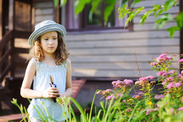 小さい庭師子女の子のトリミングし 夏の庭でシモツケ ブッシュをカットすること 季節の庭仕事 — ストック写真