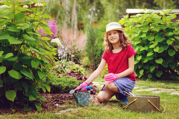 子供の女の子小さな庭師の再生を行い 夏の庭 着て帽子と手袋 ツールでの作業 — ストック写真