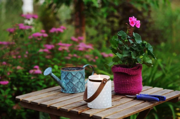 夜のキャンドル ライト ポットとビンテージの水まき缶でゼラニウムの花で庭の夏シーン居心地の良い — ストック写真