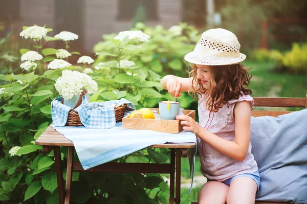 朝の夏の庭のレモンでお茶を飲んで幸せな子供女の子 — ストック写真