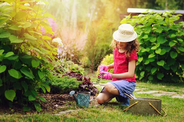 子供の女の子小さな庭師の再生を行い 夏の庭 着て帽子と手袋 ツールでの作業 — ストック写真
