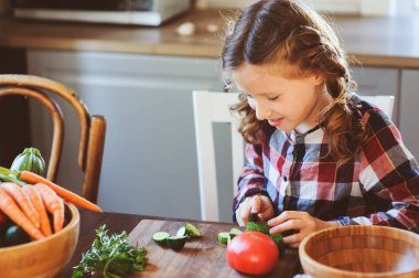 kız çocuk anne yemek ve salata için taze sebze bıçak ile kesmek için yardımcı olur. Çocuklar evi öğrenme çiftlikte yaz tatillerini üzerinde çalışmak.
