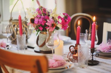 Güzel kır evinde yaz şenliği masası. Masa pembe çiçekler ve mumlarla süslenmiş..